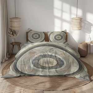 May include: A neutral-toned bedding set with a circular, mandala-like design. The duvet cover and two pillowcases feature concentric circles in shades of beige, gray, and blue. The bed is set on a round, woven rug, creating a calming bedroom aesthetic.
