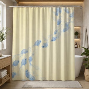 May include: A cream-colored shower curtain featuring a repeating pattern of translucent blue fish swimming in a diagonal formation. The fabric displays a soft watercolor aesthetic with varying shades of blue creating depth across the light background.