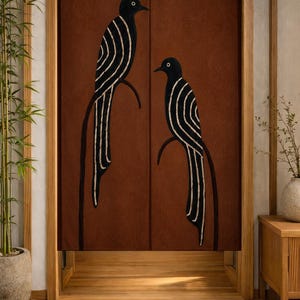 Può includere: Una tenda da porta rettangolare in tessuto con uno sfondo color terracotta intenso e due uccelli neri appollaiati su rami curvi. Ogni uccello è decorato con motivi a linee bianche curve sulle ali e sul corpo.