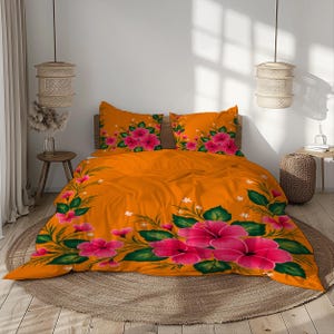 May include: Orange floral bedding set featuring large pink hibiscus flowers and green leaves. The set includes a duvet cover and two pillowcases. The bedding is placed on a bed with a round woven rug.