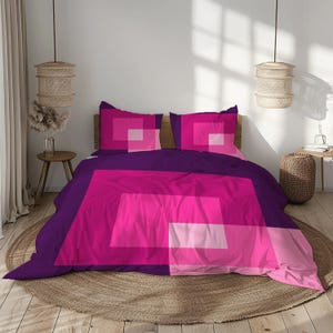 Puede incluir: Juego de cama moderno con un diseño geométrico en tonos morados y rosas. La ropa de cama incluye una funda nórdica y dos fundas de almohada. El diseño incorpora cuadrados y rectángulos grandes, creando un aspecto audaz y contemporáneo.