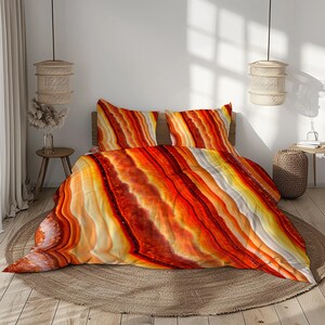 May include: A bed dressed with a striking duvet cover and pillowcases. The bedding features a layered, abstract pattern in orange, yellow, and white, reminiscent of agate. The bed sits on a circular woven rug. The room has a natural, earthy aesthetic.