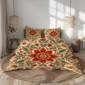 Könnte beinhalten: Ein Bettwäscheset bestehend aus einem Bettbezug und zwei passenden Kissenbezügen mit einem symmetrischen Blumenmuster in Dunkelrot, Orange und Salbeigrün auf cremefarbenem Grund, das große zentrale Blüten und verschlungene Ranken zeigt.