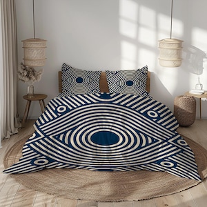 Könnte beinhalten: Ein marineblaues und cremefarbenes Bettwäsche-Set mit einem augenartigen geometrischen Muster. Das Set beinhaltet einen Bettbezug und zwei Kissenbezüge. Das Design besteht aus konzentrischen Kreisen und geschwungenen Linien, die eine moderne, abstrakte Ästhetik erzeugen.
