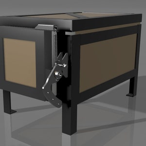 Może przedstawiać: Czarne metalowe pudełko z drzwiami na zawiasach i sprężynowym zatrzaskiem. Pudełko stoi na czterech nogach i ma brązowe wnętrze.