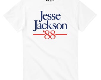 May include: White t-shirt featuring the name "Jesse Jackson" in navy blue, with "'88" in red, and a red line underneath. The shirt has a crew neck and short sleeves. The Dark Icon logo is visible on the upper left.