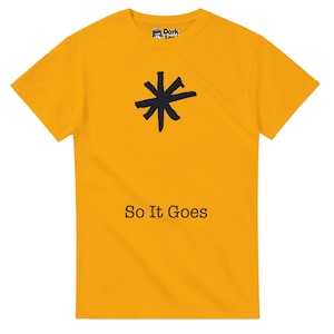 May include: Mustard yellow t-shirt featuring a black asterisk design and the text "So It Goes" in black. The shirt has a crew neck and short sleeves. The brand logo is visible on the upper left.