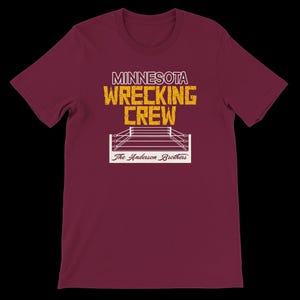May include: Maroon t-shirt with the text "MINNESOTA WRECKING CREW" in yellow and white. Below the text is a white illustration of a wrestling ring, with the text "The Anderson Brothers" below the ring.