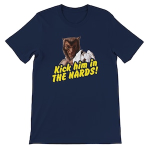 May include: Navy blue t-shirt featuring a werewolf graphic with the text "Kick him in THE NARDS!" in yellow. The werewolf is depicted with a menacing expression. A humorous and bold graphic tee.