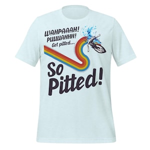 May include: Pale blue t-shirt with a graphic design. The design features a rainbow-coloured wave, a butterfly, and the words "WAHPAAAH! PUUUAHHH! Get pitted... So Pitted!" in black and white text. The shirt is made of a soft material.
