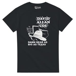 May include: Black t-shirt featuring a white graphic of a cowboy hat, a map of Texas, and the text "DAVID ALLAN COE" and "DAMN NEAR AS BIG AS TEXAS". The shirt also includes the text "The Mysterious Rhinestone Cowboy".
