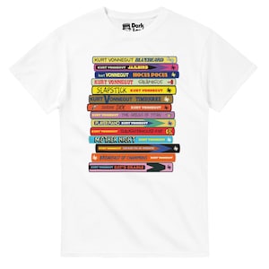 以下が含まれることがあります： カート・ヴォネガットの書籍タイトルが積み重ねられたデザインの白いTシャツ。「Bluebeard」や「Cat's Cradle」などのタイトルが含まれています。カラフルな本の背表紙が特徴です。クルーネックと半袖です。