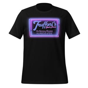 Può includere: T-shirt nero con un design al neon per "Truffoni's Steak House". L'insegna ha una combinazione di colori viola e blu con il testo "No Sloppy Steaks, No Pieces of Shit."
