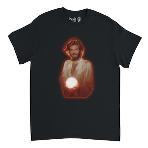 Pode incluir: Camiseta preta com um gráfico de uma pessoa segurando um orbe brilhante, com uma contorno vermelho. A pessoa tem cabelo comprido e usa uma camisa branca. O logotipo Darkside está no canto superior direito.