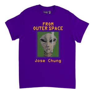 Op de afbeelding: Paars T-shirt met een afbeelding van een alien die een sigaret rookt, met de tekst "FROM OUTER SPACE" en "Jose Chung" in het geel. De alien staat tegen een groene achtergrond in een blauwe rand.