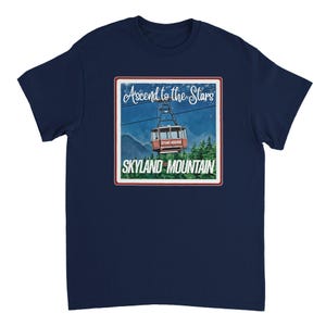 May include: A navy blue t-shirt with a graphic of a red cable car ascending a mountain, with the text "Ascend to the Stars" and "Skyland Mountain" in a white and red frame. The design is reminiscent of a vintage travel poster.