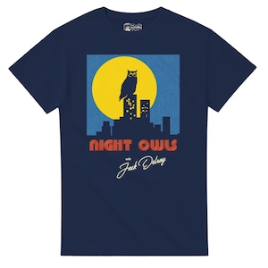May include: Navy blue t-shirt featuring a graphic of an owl perched on a cityscape against a yellow moon. The text "NIGHT OWLS with Jack Delroy" is displayed below the graphic. The shirt has a crew neck and short sleeves.