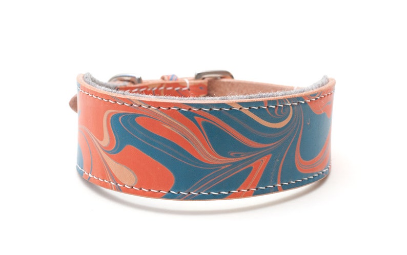 May include: A leather dog collar with a marbled pattern in shades of orange, blue, and beige. The collar has a silver buckle and white stitching.