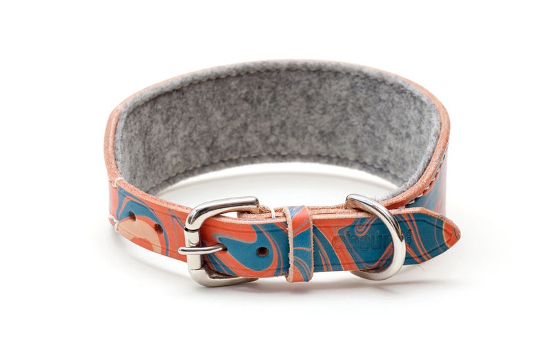 May include: A colorful leather dog collar with a blue and orange marbled pattern. The collar has a silver buckle and a gray felt lining.