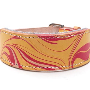 May include: A wide leather dog collar with a yellow and red marbled pattern. The collar is stitched with white thread and has a metal buckle. The collar is approximately 2 inches wide.