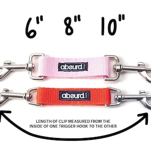 May include: Two dog leashes with silver trigger clips and a pink and orange strap. The leashes are labeled "abaurd" and measure 6 inches, 8 inches, and 10 inches. The text "LENGTH OF CLIP MEASURED FROM THE INSIDE OF ONE TRIGGER HOOK TO THE OTHER" is written below the leashes.