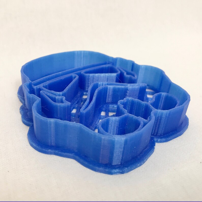 May include: A blue plastic cookie cutter shaped like a Star Wars Stormtrooper helmet.