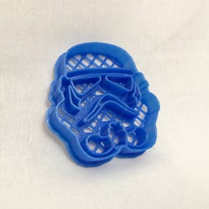 May include: A blue plastic cookie cutter shaped like a Star Wars Stormtrooper helmet.