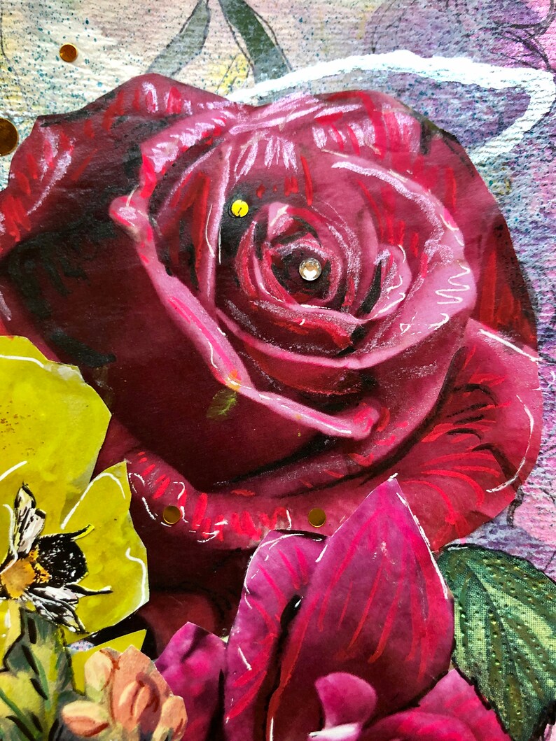 Puede incluir: Primer plano de una rosa roja con un centro blanco. La rosa est&aacute; rodeada de otras flores, incluida una flor amarilla con una abeja sobre ella.