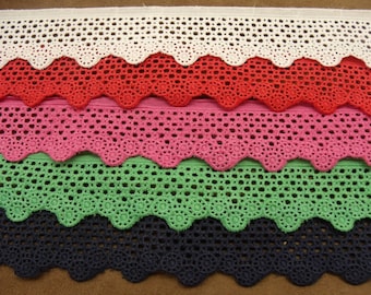May include: Four different colours of crochet trim with a scalloped edge. The colours are white, red, pink, and green.