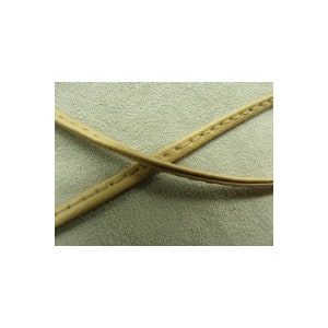 May include: Two thin, light tan leather cords crossing each other, each featuring a single line of visible stitching running along the center. The cords are set against a textured, light gray surface with a soft, matte appearance.