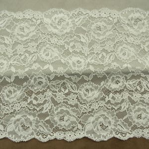 Könnte beinhalten: Weiße Spitzenborte mit Blumenmuster. Die Spitze hat einen gewellten Rand.