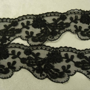 以下が含まれることがあります： 繊細な花柄の黒いレーストリム。レースは波状の縁取りになっており、透き通った生地で作られています。
