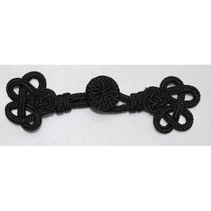 Peut inclure: Bouton en tissu noir noué avec une pièce centrale ronde. Ce bouton est utilisé pour la fermeture des vêtements.