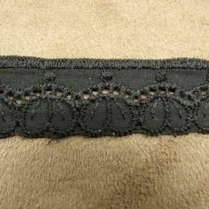 May include: Black lace trim with a scalloped edge and a repeating pattern of small circles.