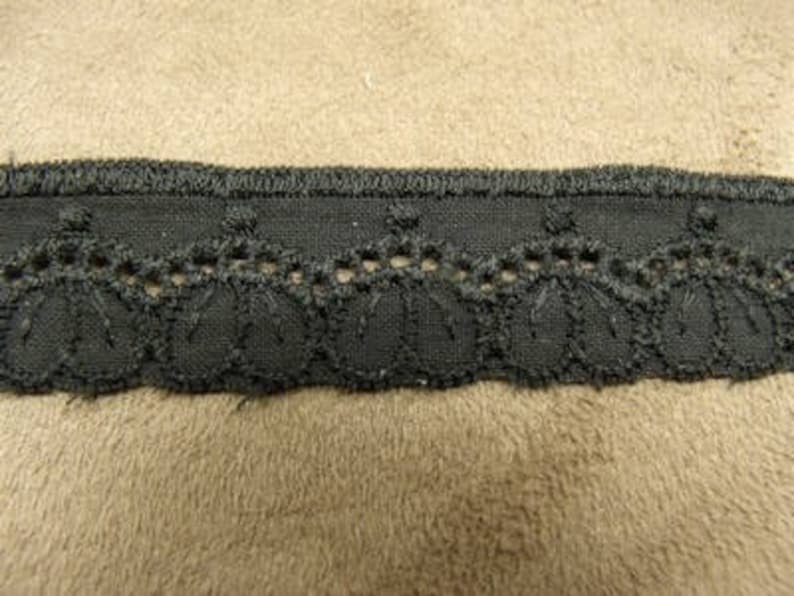 May include: Black lace trim with a scalloped edge and a repeating pattern of small circles.