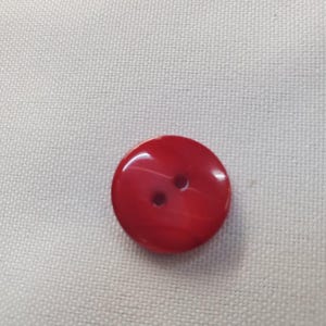 Könnte beinhalten: Ein runder, roter Knopf mit zwei Löchern. Der Knopf hat eine glänzende Oberfläche und eine leicht strukturierte Oberfläche. Der Knopf ist von leuchtend roter Farbe.