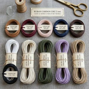 May include: A collection of 2mm waxed cord coils in various colours including tan, burgundy, pale pink, navy, brown, white, black, olive green, lavender, and beige. Each coil features a paper label with text and is tied with twine.