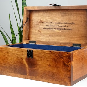 May include: A wooden box with a hinged lid and a metal chain. The lid is open and the inside is lined with blue velvet. The box is engraved with the text: "I have come with no expectations. Only to profess, now that I am at liberty to do so, that my heart is and always will be yours."