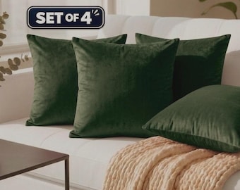 Puede incluir: Un juego de cuatro cojines cuadrados de terciopelo verde oscuro. Los cojines presentan una textura de tela lisa y de color sólido. Una etiqueta rectangular oscura con el texto blanco SET OF 4 se sitúa sobre los cojines en la parte superior.
