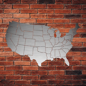 May include: A metal cutout of the United States map with each state outlined. The map is mounted on a brick wall.