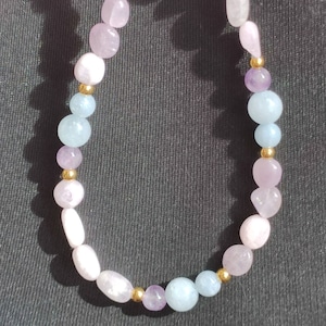 May include: A multi-coloured beaded necklace with pink, blue and purple stones separated by gold beads.