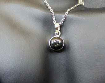 May include: A silver chain necklace with a black gemstone pendant. The pendant is round and has a smooth, polished surface.