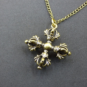 May include: A gold-coloured pendant necklace with an ornate, cross-shaped charm. The charm has a textured, antique finish and hangs from a delicate chain. The pendant's design includes intricate patterns and symmetrical elements.
