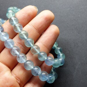 May include: A light blue gemstone bracelet with round beads. The bracelet is made of natural stones and is approximately 7 inches in length.