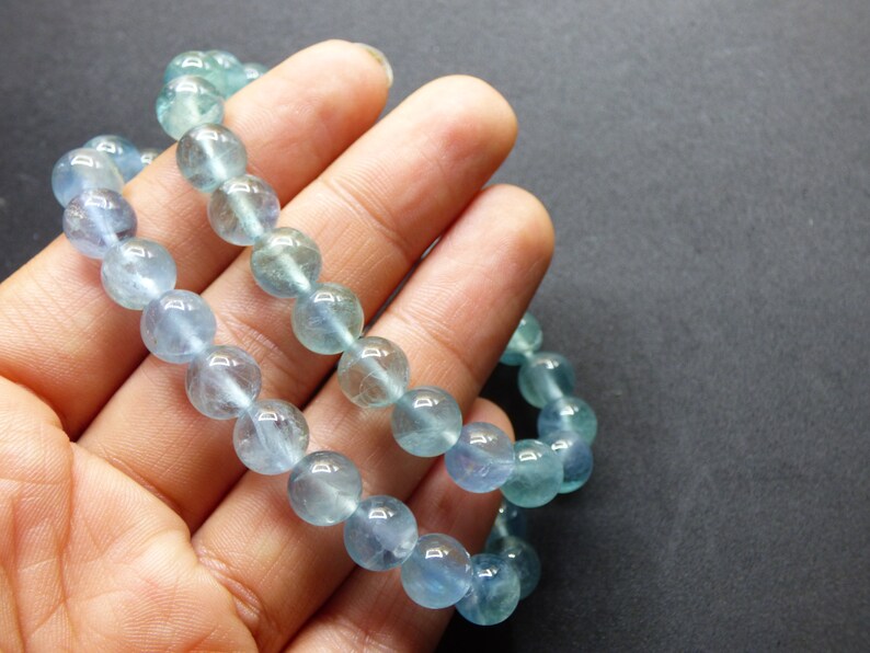 May include: A light blue gemstone bracelet with round beads. The bracelet is made of natural stones and is approximately 7 inches in length.