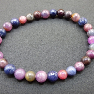 Peut inclure: Un bracelet composé de perles rondes en pierres précieuses multicolores. Les perles sont de nuances de rose, de violet et de bleu.