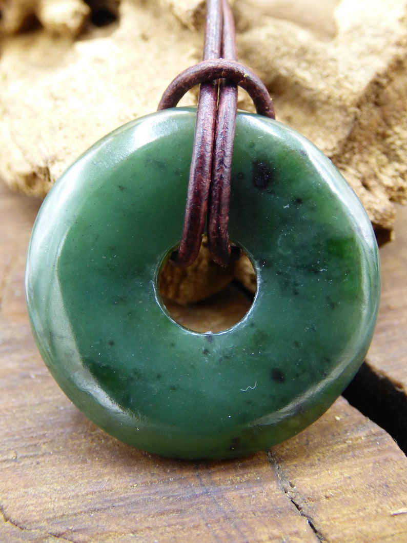 Pu&ograve; includere: Un ciondolo in giada verde a forma di anello, con un cordino in pelle marrone.