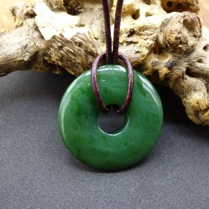 Pu&ograve; includere: Un ciondolo in giada verde a forma di ciambella, con un cordoncino in pelle marrone.