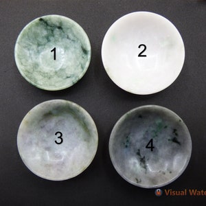 Può includere: Quattro piccole ciotole rotonde di giada con i numeri da 1 a 4 scritti su di esse. Le ciotole sono disposte in una griglia 2x2 su una superficie nera.
