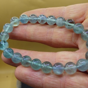 May include: A bracelet made of light blue gemstone beads. The beads are round and have a slight shimmer to them.